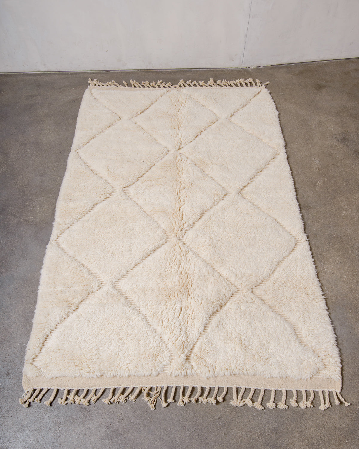 Berberlin Beniourain rug made of cream wool laying flat on concrete floor.